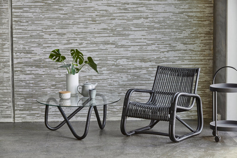 Coffee table with a wavy rattan base and a sleek, round glass top